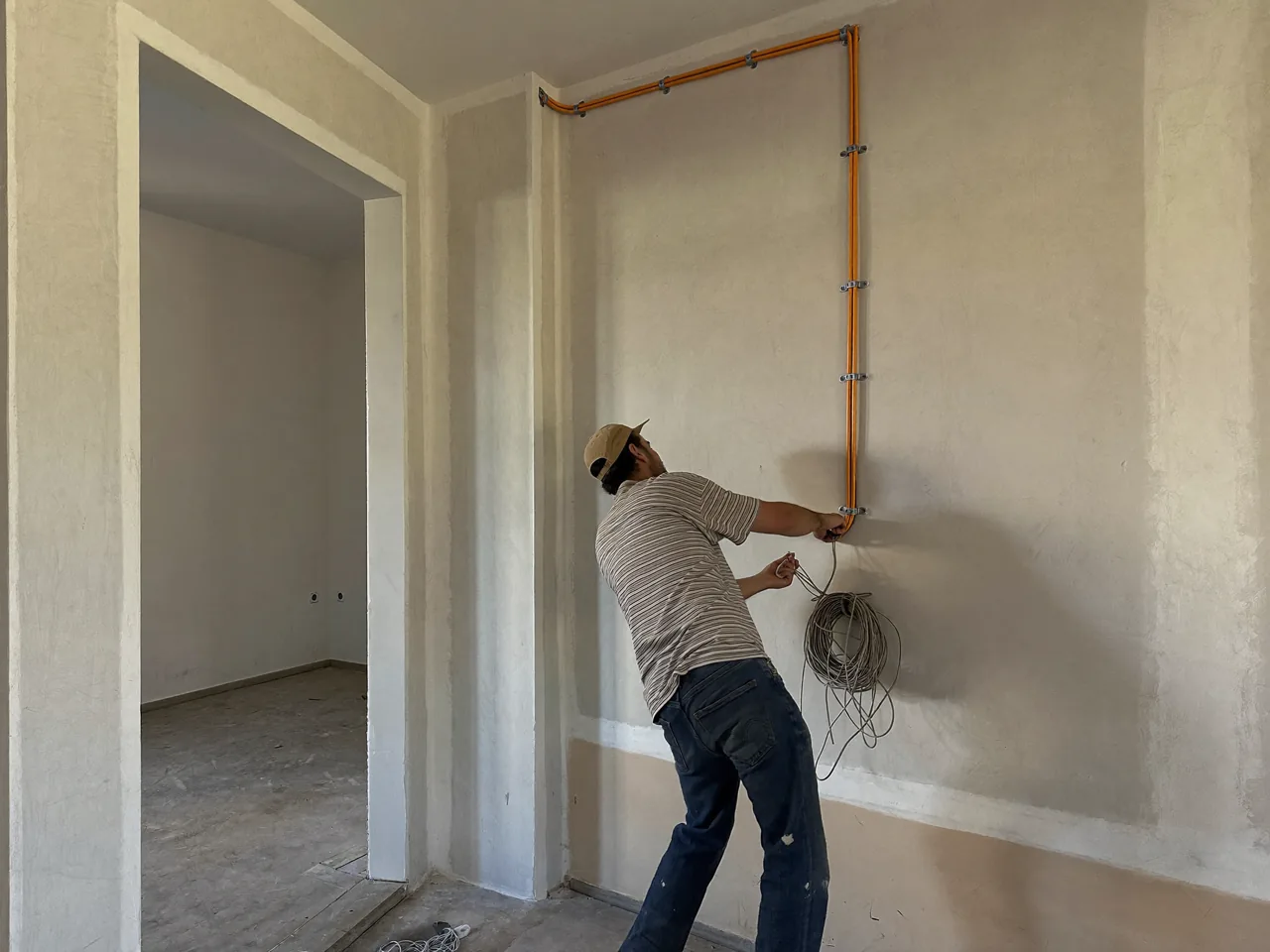 Electricista pasando cableado por tubo corrugado en una vivienda reformada de Rubí